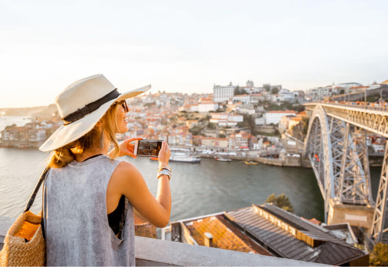 woman takes photo in Porto with bridge